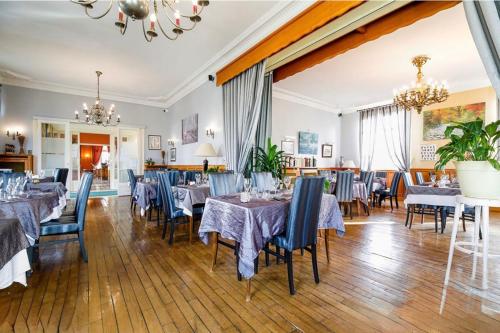 a dining room with tables and chairs and a chandelier at Le Renaissance in Montdidier