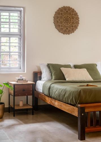 a bedroom with a bed and a table and a window at Chetty's Mane by Raho - Estate-View Heritage Stay in Siddapur