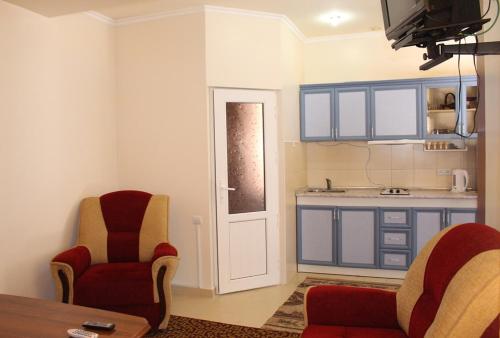 a living room with two chairs and a kitchen at Shushanik Home in Jermuk