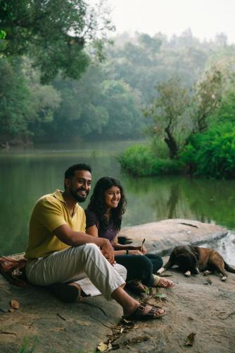 a man and woman sitting on a rock with a dog at Chetty's Mane by Raho - Estate-View Heritage Stay in Siddapur
