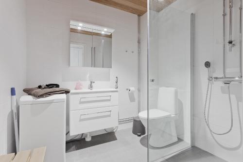 uma casa de banho branca com um chuveiro e um WC. em Forenom Serviced Apartments Turku Kakolanmäki em Turku