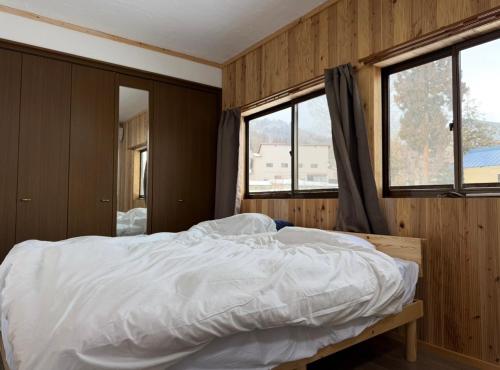 a bedroom with a white bed with two windows at Kamakura in Iiyama