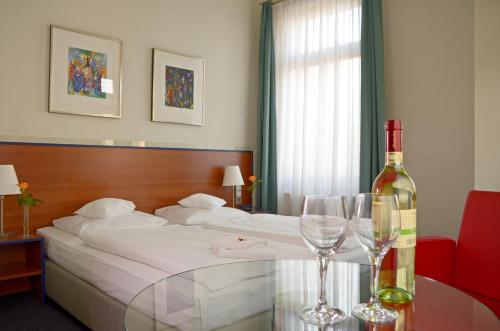 a hotel room with a bed with a bottle of wine at Hotel & Apartments Fürstenhof am Bauhaus in Weimar