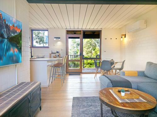 a living room with a couch and a table at The Hideaway - Lake Views I Ski & Bike Storage I Central Jindabyne I Free WiFi I BBQ I Parking in Jindabyne