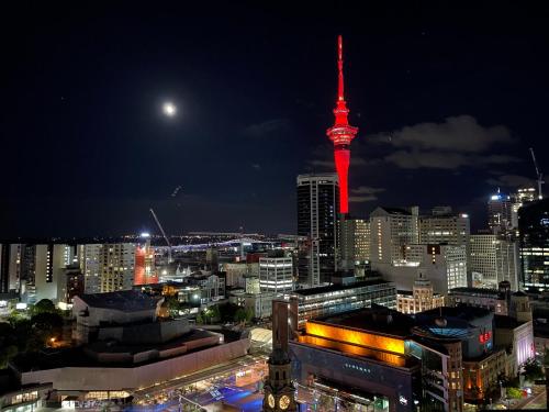 a view of a city at night with a red tower at Magnificent Skytower View 2 Bedroom 2 Bathroom Apartment in Auckland