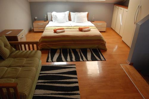 a bedroom with a bed with two pillows and a couch at Car Royal Apartments and Rooms in Novi Sad