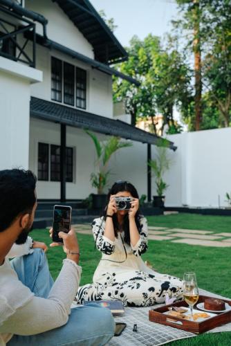 a woman taking a picture of a man with a camera at Okka by Raho - A colonial style villa in Coorg in Siddapur