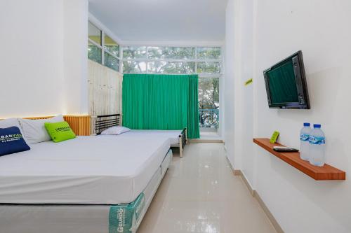 two beds in a room with a green curtain at Urbanview Hotel near Exit Tol BSD in Ciater-hilir