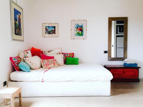 a room with a white bed with colorful pillows at Lovely Central Apartment in Talamone