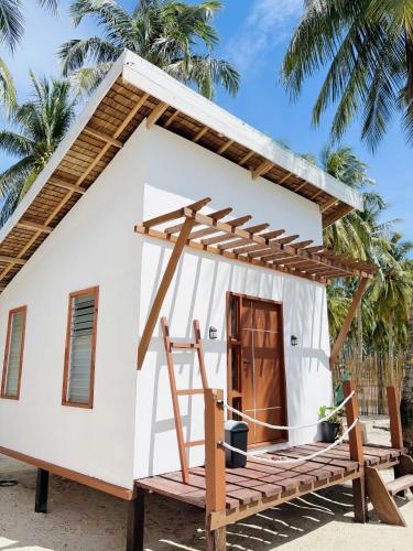 a small white house with a porch and a wooden door at Tatak Balabac Beach Camp in Olorga
