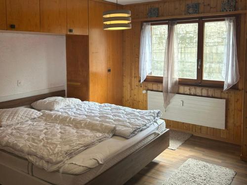 a bed in a room with wooden walls and windows at Apartment in Veysonnaz with pool in Veysonnaz
