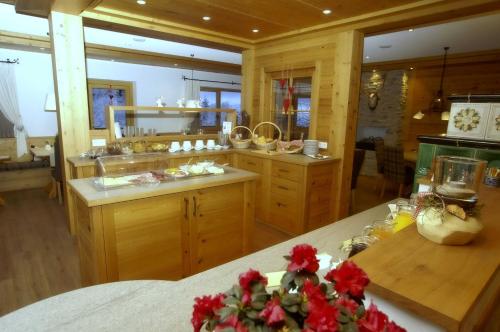 a kitchen with wooden cabinets and red flowers on a counter at Hotel zum Breitenberg in Bad Peterstal