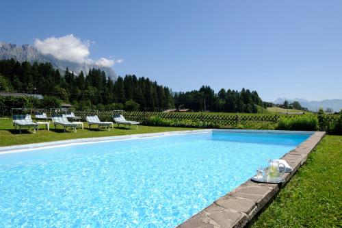 a swimming pool in a field with chairs and trees at Hotel Blattlhof in Going am Wilden Kaiser