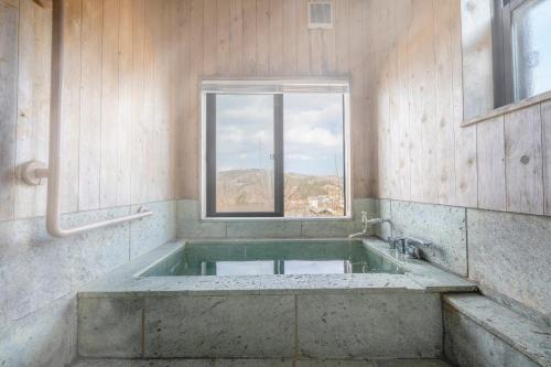 a large bath tub in a room with a window at 天然温泉-富士山パノラマビュー-プライベートデッキで非日常体験を-伊豆の温泉付き貸別荘-中伊豆noie in Izu