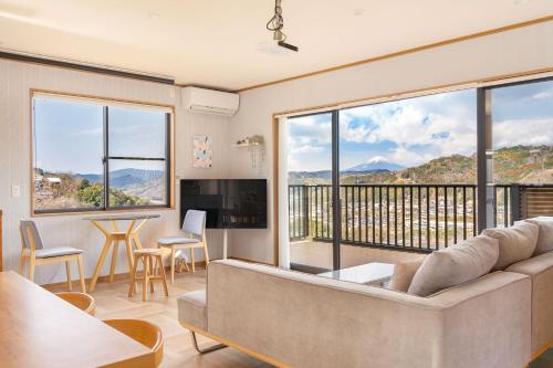 a living room with a couch and a large window at 天然温泉-富士山パノラマビュー-プライベートデッキで非日常体験を-伊豆の温泉付き貸別荘-中伊豆noie in Izu