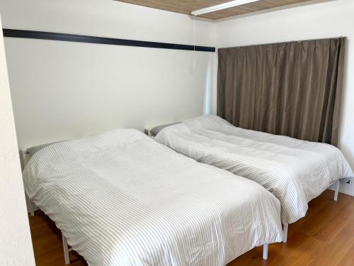 two beds in a room with white sheets at フレグランスショーワ in Matsue