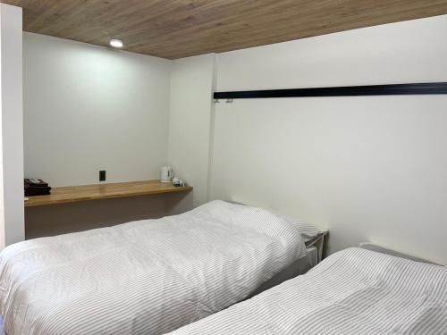 two beds in a bedroom with white walls at フレグランスショーワ in Matsue