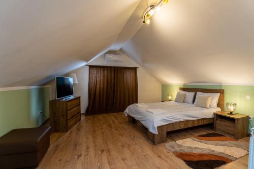 a bedroom with a large bed and a television at Grandma’s Cottage in Săcele