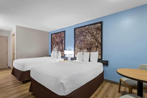 two beds in a room with blue walls and a table at Super 8 by Wyndham Valdosta GA I-75 in Valdosta