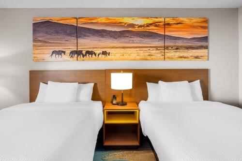 a hotel room with two beds and a painting of horses at Days Inn & Suites by Wyndham Ridgeland in Ridgeland