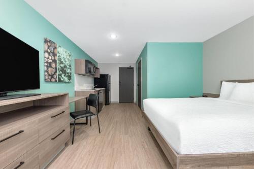 a hotel room with a bed and a tv at ECHO Suites Extended Stay by Wyndham Dallas Plano Richardson in Plano