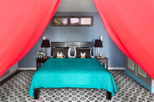 a bedroom with a green bed with red curtains at Owl and the Pussycat Hotel & Restaurant in Unawatuna