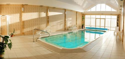 a large indoor pool with chairs and a tub at Hotel Zolota Pidkova in Kozlin