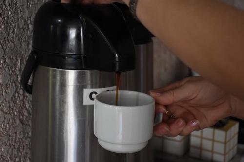 a person is pouring coffee into a coffee cup at Hotel Holiday Foz in Foz do Iguaçu