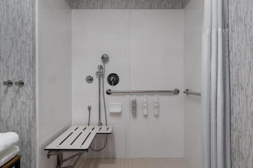 a white bathroom with a bench and a shower at Hampton Inn Owensboro in Owensboro