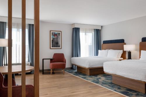 a hotel room with two beds and a chair at Hampton Inn Owensboro in Owensboro