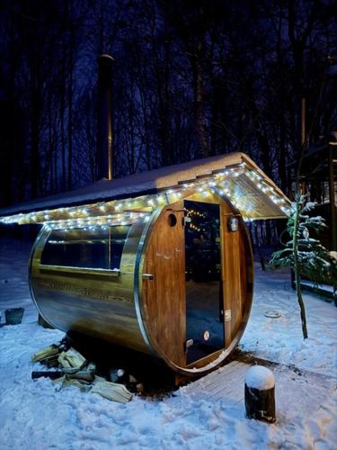 a wooden barrel with lights on it in the snow at Treehous Sněžník s wellness in Dolní Morava