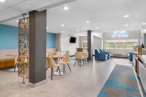 a waiting room with tables and chairs in a building at Days Inn & Suites by Wyndham Brandon Amphitheater in Brandon