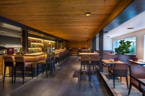 un ristorante con soffitti e tavoli in legno e sedie di Hotel Cristallo - Wellness Mountain Living a La Villa