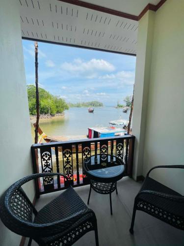 a balcony with chairs and a view of a river at Libong River View in Ban Maphrao (2)