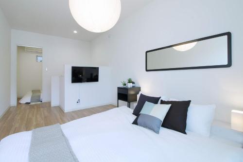 a bedroom with a white bed and a television at b hotel Ball Park - Apt 2mins to Baseball 5mins to Hiroshima Sta 4ppl in Hiroshima