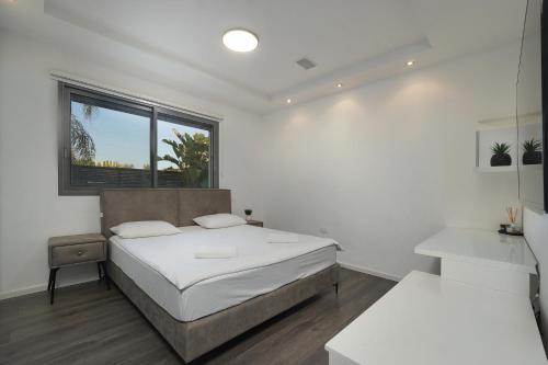a white bedroom with a bed and a window at S Villa Place נהריה in Nahariyya
