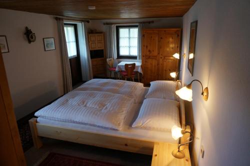a bedroom with a bed with two white sheets and lights at Ferienhaus Birkenhof in Afritz