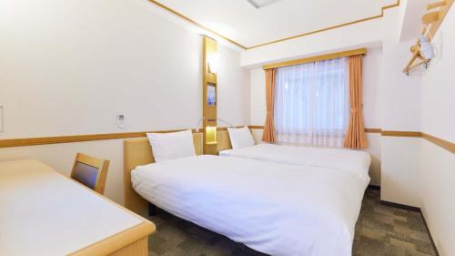 a hotel room with two beds and a window at Toyoko Inn Fukui Ekimae in Fukui