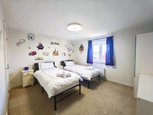 two beds in a room with blue curtains at Bright 4BR Family Retreat mins from Harry Potter in Leavesden Green