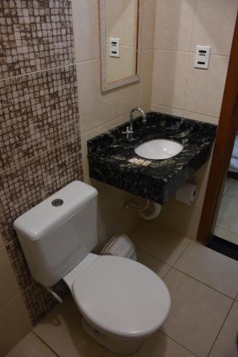 a bathroom with a white toilet and a sink at Hotel Holiday Foz in Foz do Iguaçu