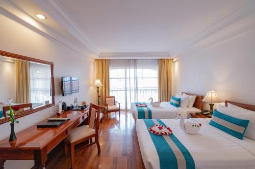 a hotel room with two beds and a desk at Somadevi Angkor Premium in Siem Reap