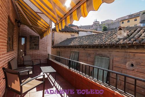 a balcony with tables and chairs on a building at Apartamentos Adarve Toledo in Toledo