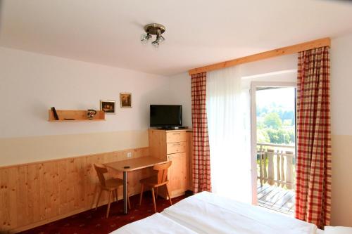a bedroom with a bed and a desk with a television at Pension Sonnengrund in Reifnitz