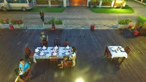 a group of people sitting at tables in a courtyard at Senesothxuene Hotel in Muang Không