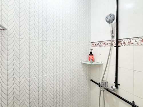 a shower with a white tiled wall at RedDoorz Plus near Brawijaya Museum in Malang