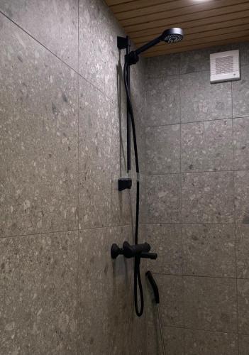 a shower in a bathroom with a shower head on a wall at RUSKA-mökki in Tyrnävä
