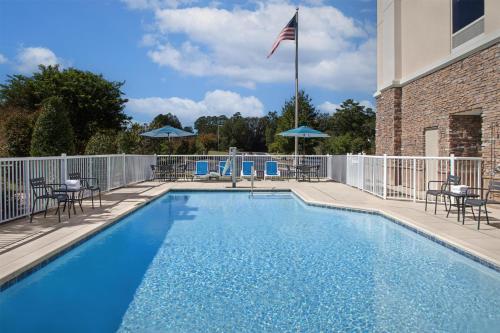 a swimming pool with chairs and a flag on a building at Hampton Inn and Suites Fayetteville, NC in Fayetteville