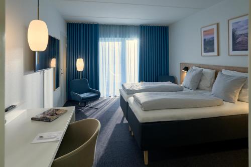 a hotel room with a large bed and a desk at Hotel Faaborg Fjord in Faaborg