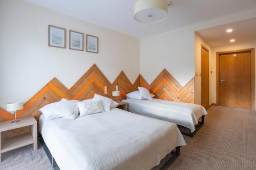 a bedroom with two beds and a wooden wall at Novobilski przy Termie Bania i Kotelnicy - sauna, jacuzzi, restauracja, pokój zabaw, wypożyczalnia rowerów e-bike in Białka Tatrzańska