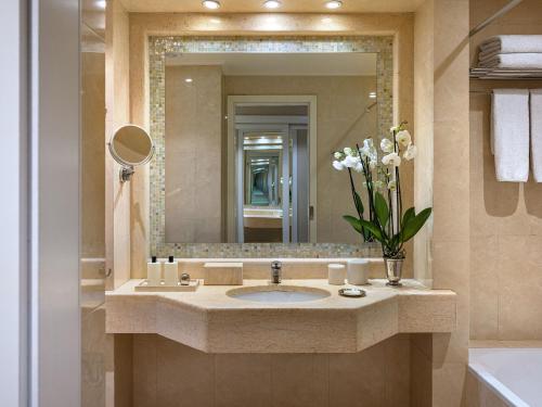 a bathroom with a sink and a large mirror at Grecotel Larissa Imperial in Larisa